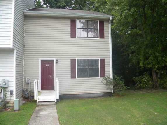 Front view of a two-story townhouse with a red door and windows with shutters.