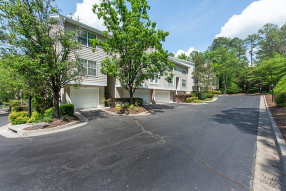 Front view of a multi-story house with a garage and surrounding trees.