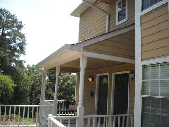 Front view of a house with a covered porch and railing.