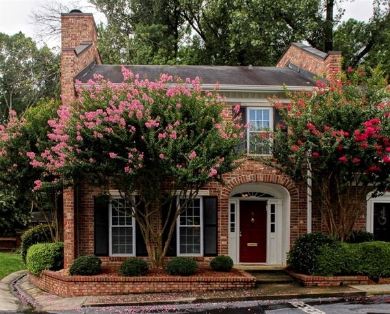 Front view of a two-story brick house with a central entrance and surrounding foliage.