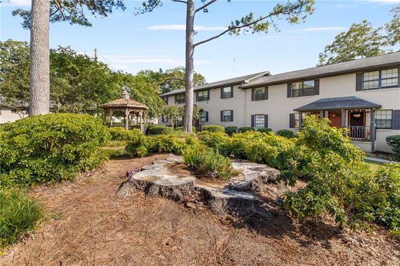 Front view of a two-story building with a garden and gazebo in front.