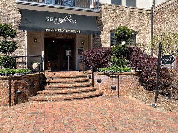 Front view of a building entrance with brick steps and awning.