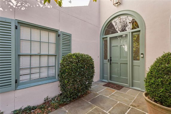 Front view of a house entrance with green door and shutters.