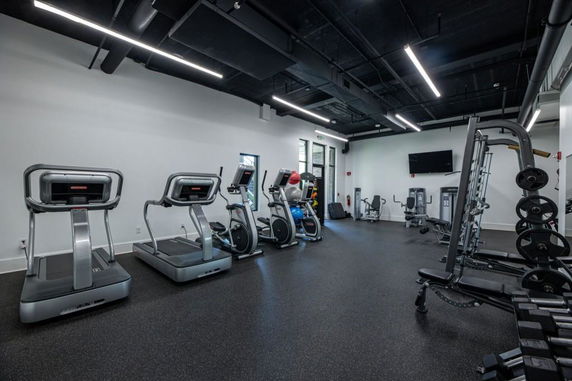 Indoor gym area with exercise equipment including treadmills, stationary bikes, and weights.