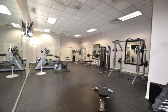 Gym area with exercise equipment and mirrors on the wall.