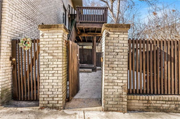 Front view of a house entrance with a brick fence and wooden gate.