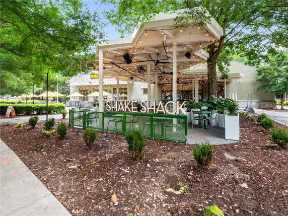 Front view of an outdoor seating area with a Shake Shack sign and string lights.