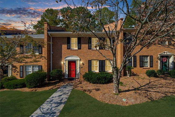 Front view of a two-story brick house with a red door.