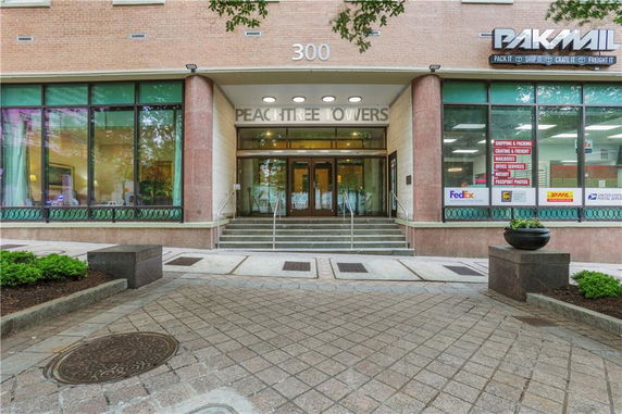 Front view of a building with large glass windows and the name 'Peachtree Towers' above the entrance.