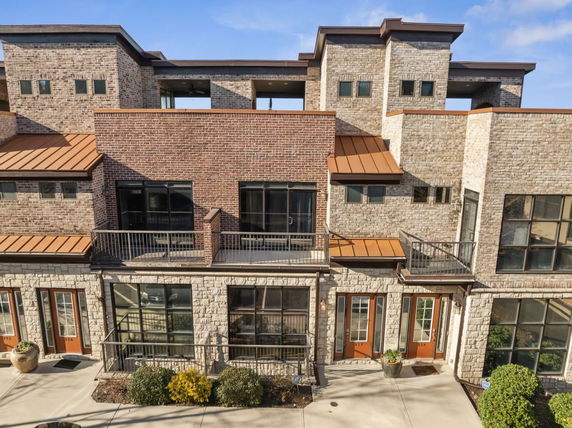 Front view of a multi-story building with brick and stone facade, balconies, and multiple windows.