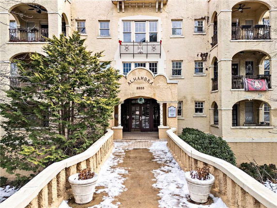 Front view of a multi-story building with balconies and an arched entrance.