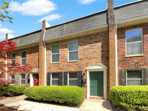 Front view of a two-story townhouse with brick exterior and green door.