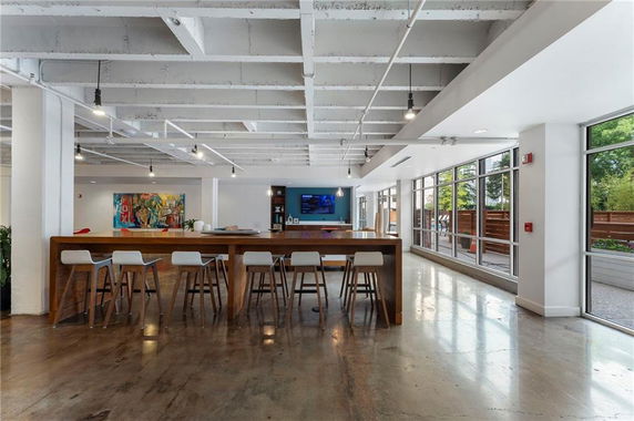 Interior view of a modern club house with a long table and bar stools.