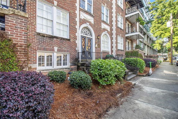 Front view of a brick apartment building with decorative entrance and arched windows.