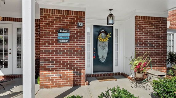 Front view of a brick house with a covered porch and decorative front door.