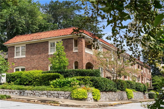 Front view of a brick building with red tile roof and lush landscaping.