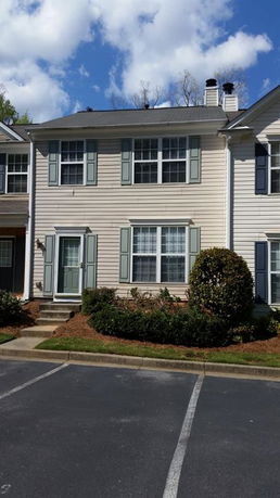Front view of a two-story townhouse with a single front door and two chimneys.