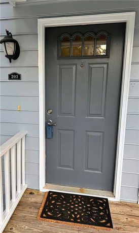 Front view of a residential entrance with a gray door and a decorative mat.