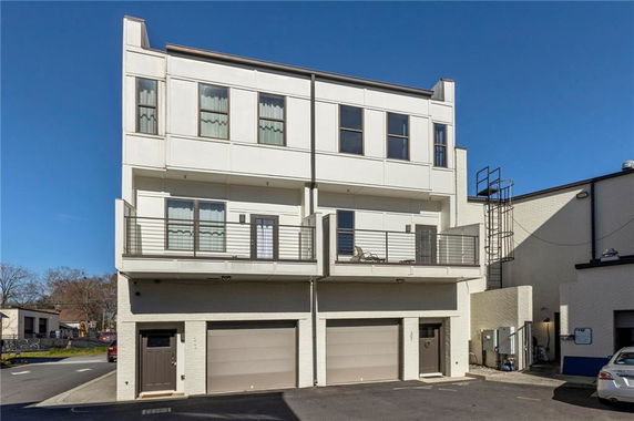 Front view of a modern three-story building with balconies and a garage