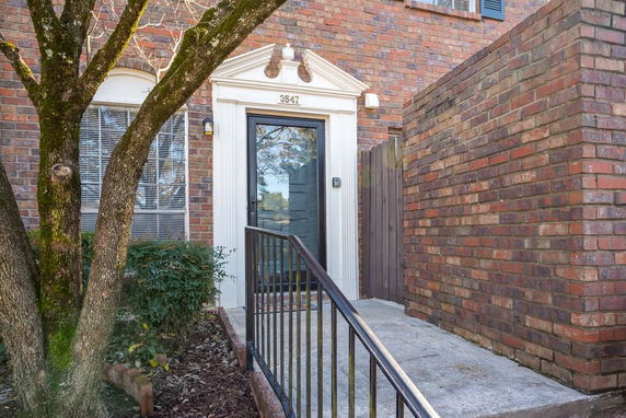 Front view of a brick house entrance with a door and a small porch area.