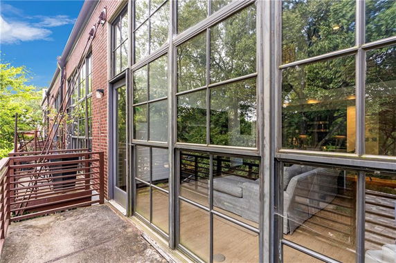 Exterior view of a brick building with large glass windows and a small balcony.