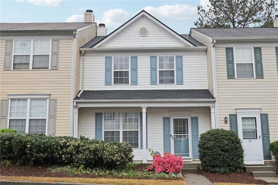 Front view of a white two-story townhouse with blue shutters and a small porch.