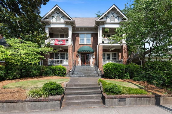 Front view of a two-story brick house with a porch and green awning.