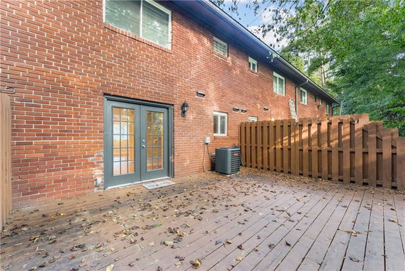 Brick exterior of a two-story building with a deck and wooden fence.