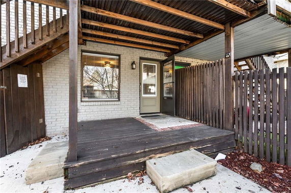Rear view of a house with a wooden deck and stairs.