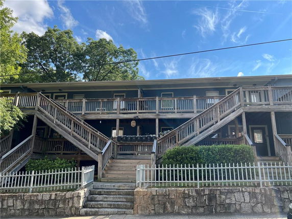 Front view of a two-story building with exterior wooden stairs and railing.