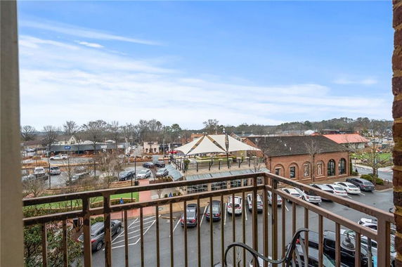 View from a balcony overlooking a parking area and surrounding buildings.