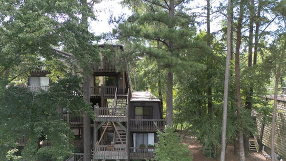 Front view of a multi-story building with wooden exterior surrounded by trees.