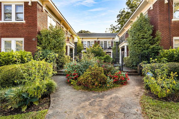 Front view of a brick residential building with a gated entrance and landscaped garden.