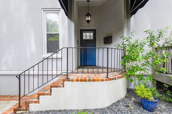 Front view of a house entrance with a blue door and brick steps.