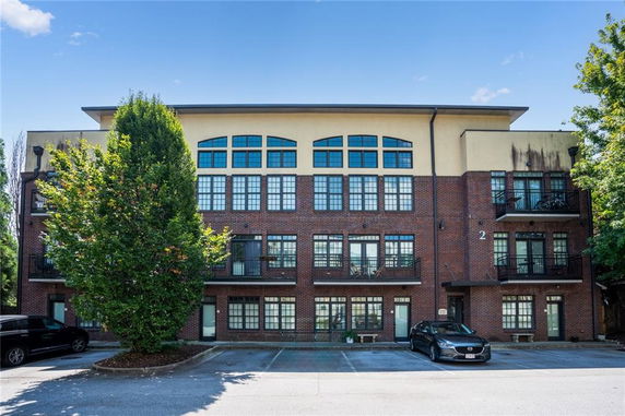Front view of a multi-story brick building with large windows and balconies.