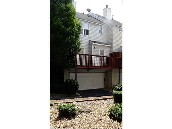Front view of a multi-story house with a garage and an elevated patio.