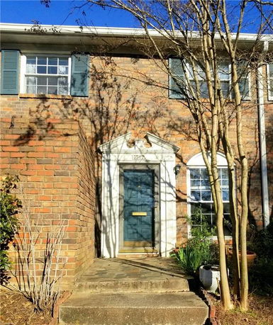 Front view of a brick house with a blue door and white trim.