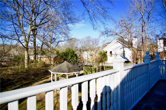 Panoramic view from a balcony showing trees and neighboring houses.