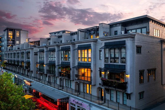 Front view of a multi-story building at dusk with illuminated windows.