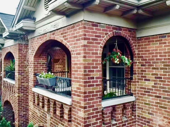 Front view of a brick house with arched windows and decorative railings.