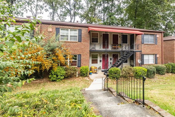 Front view of a two-story brick apartment building with an external staircase and a red awning.