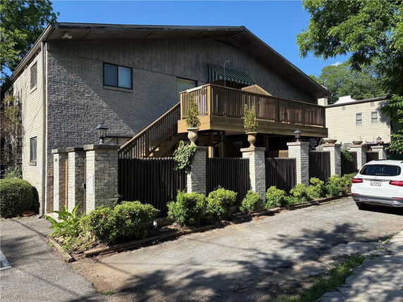 Front view of a two-story building with a wooden balcony and a brick exterior.