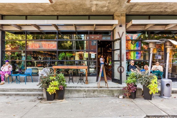 Front facade of a modern cafe with large windows and outdoor seating.