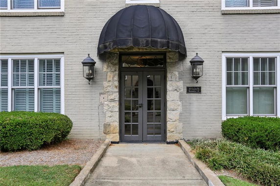 Front view of a building entrance with stone and brick exterior and black awning.