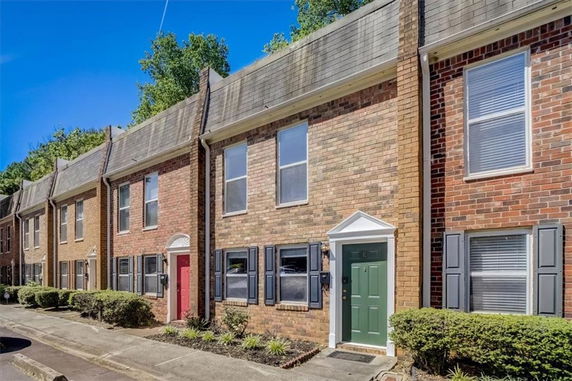 Front view of a row of brick townhouses with different colored doors.