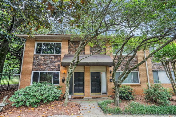 Front view of a two-story brick townhouse with stone accents and twin doors.