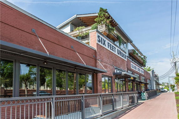 Front view of a brick building with large windows and outdoor seating area.