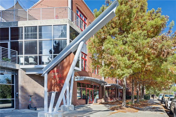 Front view of a multi-story building with large windows and an angled metal structure.