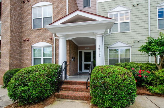 Front view of a building entrance with columns and brick steps.