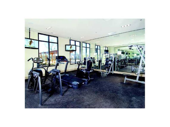 Indoor gym area with exercise equipment and large windows.